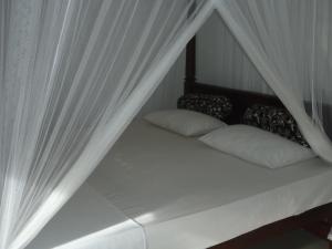 een bed met witte gordijnen en kussens erop bij New Jaya Villa in Bentota