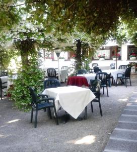 a group of tables and chairs under a tree at Camping Aquileia in Aquiléia