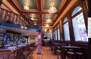 a bar with wooden stools in a room with windows at The Terminus in Dunedin