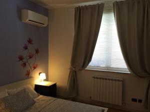 Dormitorio con ventana, cama y lámpara en Palazzina Magnolia, en San Benedetto del Tronto