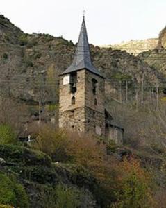 un antiguo edificio con un campanario en una montaña en La Buhardilla De Isavarre, en Isavarre