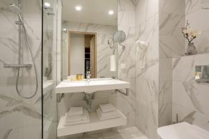 a white bathroom with a sink and a shower at Centennial Nexus Hotel Tallinn in Tallinn