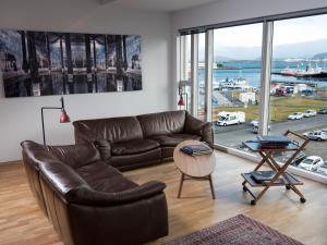 a living room with a leather couch and a large window at Reykjavík Central Apartments in Reykjavík