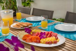 a table topped with plates of fruit and orange juice at Villa Desi in Bang Tao Beach +9 photos
