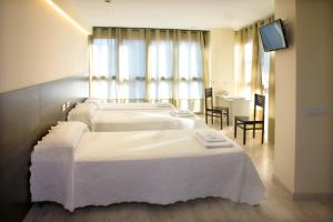 a hotel room with two beds and a television at Imprenta Musical Alojamiento in Astorga