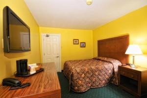 a hotel room with a bed and a desk with a telephone at Driftwood Inn in Deer Lake
