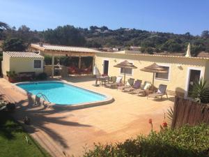 a pool with chairs and umbrellas next to a house at Casa Paula Villas - Private Heated Pool for Each House in Lagos