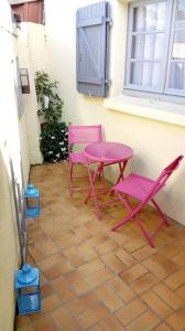 twee roze stoelen en een tafel op een patio bij La Roseraie de Gamaches in Gamaches