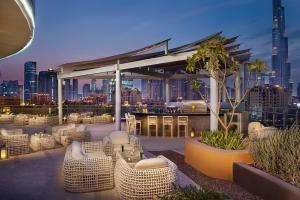 a rooftop patio with tables and chairs and a city skyline at DAMAC Maison Distinction in Dubai