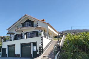 Casa blanca con balcón en la parte superior. en OurMadeira - Casa Vista Bela, countryside en Estreito da Calheta