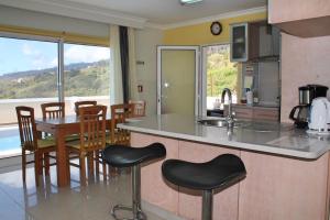 a kitchen with a counter and a table with chairs at OurMadeira - Villa Dilis, informal in Calheta