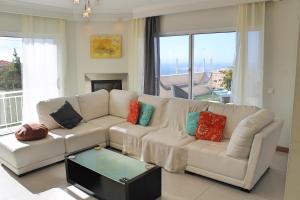 a living room with a white couch with colorful pillows at OurMadeira - Villa Dilis, informal in Calheta