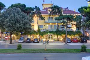 un edificio con coches estacionados en un estacionamiento en Hotel Mimosa, en Lignano Sabbiadoro