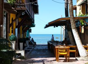 a street with tables and chairs in front of the ocean at Pousada do Pepe in Morro de São Paulo