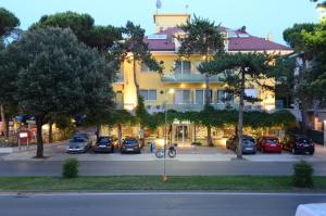 a large building with cars parked in a parking lot at Hotel Mimosa in Lignano Sabbiadoro