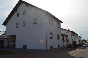 a white building with a black roof on a street at Ferienwohnung Am Neuberg in Westhofen
