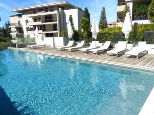 une piscine avec des chaises longues et un bâtiment dans l'établissement Luxury & Exclusive Resort, à Saint-Tropez