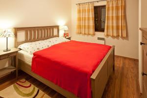 
a bed room with a red bedspread and white sheets at Apartmany Hrabovo in Ružomberok
