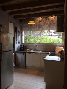 a kitchen with a refrigerator and a window at Gîte du Ruisseau de la Renne in Thésée