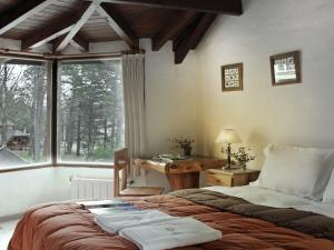 a bedroom with a bed and a desk and a window at HTL La Malinka in San Carlos de Bariloche