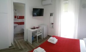 a white bedroom with a red bed and a bathroom at La Bella Vita in San Vito dei Normanni