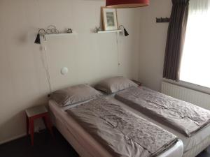 a bedroom with a bed and a window at Bed and Breakfast De Mozaiektegel Uden in Uden