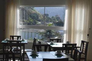 a dining room with tables and chairs and a large window at Flat Hotel Vale das Montanhas in Adrianópolis