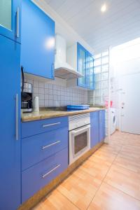 a kitchen with blue cabinets and a wooden floor at Los Robles Verdes in Maspalomas