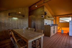 a dining room with a wooden table and chairs at MARUŠINA OLIVE HILLS - glamping & minicamp in Punat