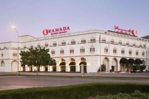 a white building with a sign on top of it at Ramada Qurum Beach Hotel in Muscat