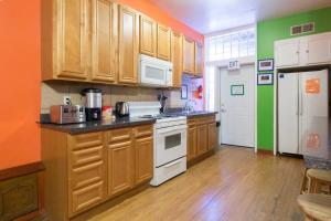una cocina con armarios de madera y electrodomésticos blancos en Wrigley Hostel - Chicago, en Chicago