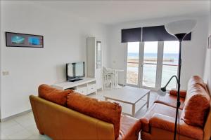 a living room with a couch and a table with a television at Edificio Playa Chica in El Médano