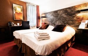 a hotel room with a bed with towels on it at Logis Hotel Lons-le-Saunier - Restaurant Le Grill in Lons-le-Saunier