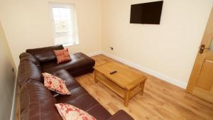 sala de estar con sofá de cuero marrón y mesa en Inish House, en Malin Head