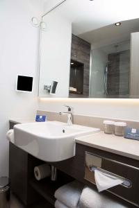La salle de bains est pourvue d'un lavabo blanc et d'un miroir. dans l'établissement Crowne Plaza Basingstoke, an IHG Hotel, à Basingstoke