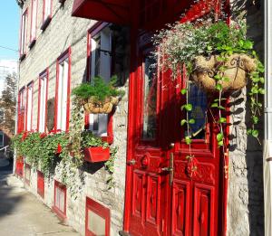 a red door on a building with potted plants at Gîte À l'Augustine in Quebec City