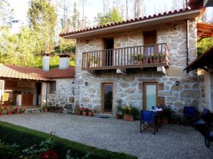 a stone house with a balcony and a patio at Casa da Eira Velha in Vale de Cambra