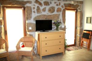 ein Wohnzimmer mit einem TV auf einer Kommode und zwei Fenstern in der Unterkunft Casa da Eira Velha in Vale de Cambra
