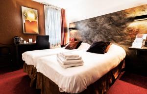 a hotel room with a bed with towels on it at Logis Hotel Lons-le-Saunier - Restaurant Le Grill in Lons-le-Saunier