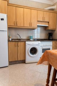 eine Küche mit einem weißen Geschirrspüler und Holzschränken in der Unterkunft Apartamento junto el mar, internet de un IG in Gran Tarajal