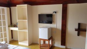 a room with a tv on a wall with shelves at Pousada Costa do Sapê in Angra dos Reis
