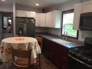 a kitchen with a table and a kitchen with white cabinets at Eycat Lodging Company Guest House in Wapiti