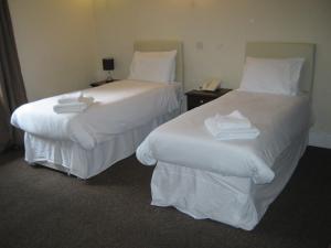 two beds in a hotel room with white sheets at Rose and Crown Hotel in Haverhill