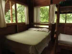 a bedroom with two bunk beds and two windows at Vocaré Finca Agroecológica in Upala