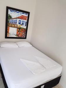 a white bed in a room with a picture on the wall at Pousada Portalcion in Goiás