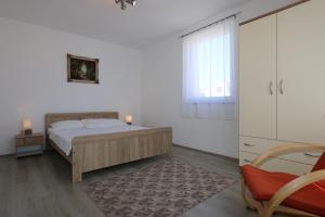 a bedroom with a bed and a window and a chair at Apartments Mihalic in Šilo