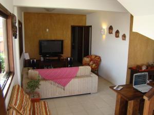 a living room with a couch and a tv at Pousada Villa Prainha in Farol de Santa Marta