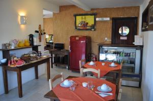 a kitchen with two tables and a red refrigerator at Pousada Villa Prainha in Farol de Santa Marta
