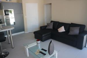 a living room with a black couch and a glass table at Maison indépendante in Marseille