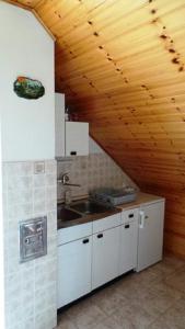 a kitchen with white cabinets and a wooden ceiling at Apartments Rozi in Bovec